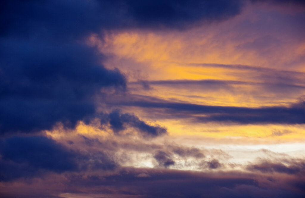 Dramatic twilight clouds blend deep blue and soft yellow tones in serene painterly wallpaper background