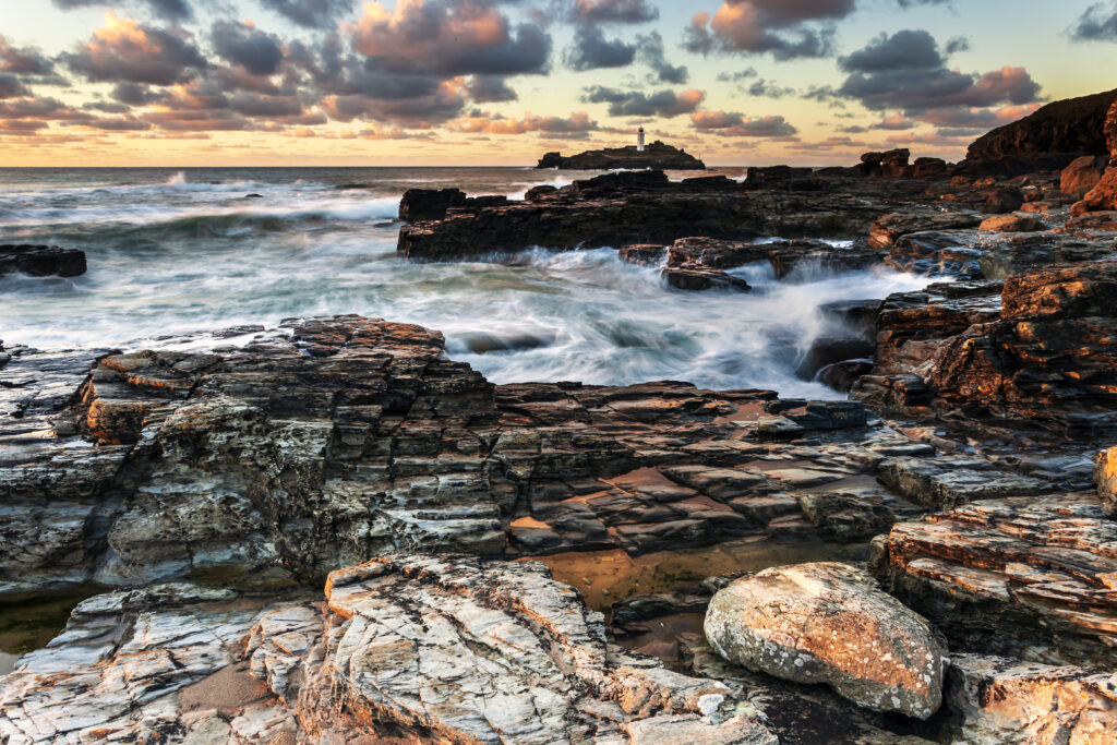 Twilight coastal landscape with rugged rocks dynamic ocean waves colorful sky wallpaper background
