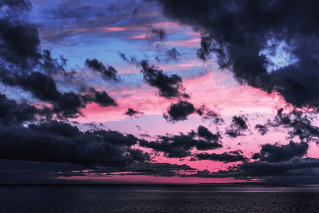 Twilight sky with pink and blue clouds over calm sea horizon dramatic atmospheric wallpaper