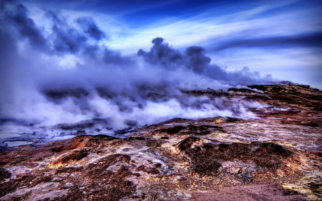 Billowing smoke over rugged volcanic landscape with mountains vivid HDR dramatic sky wallpaper