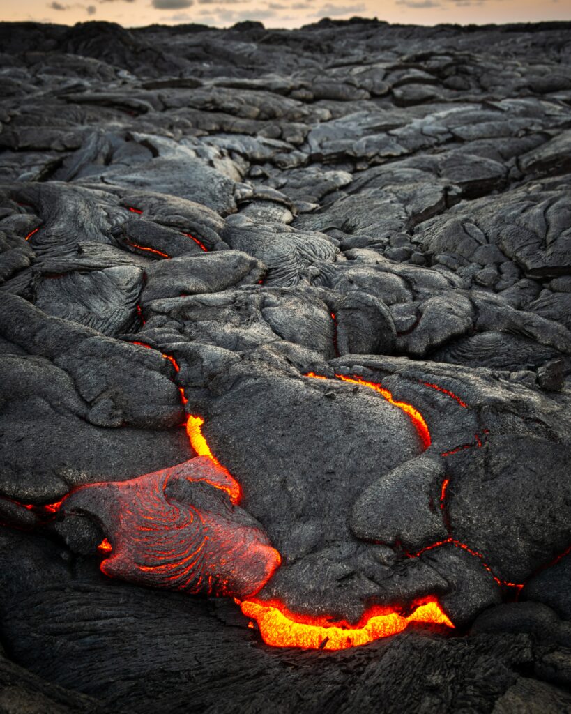 Volcanic landscape with glowing lava flowing beneath cracked rugged dark ashy surface wallpaper background