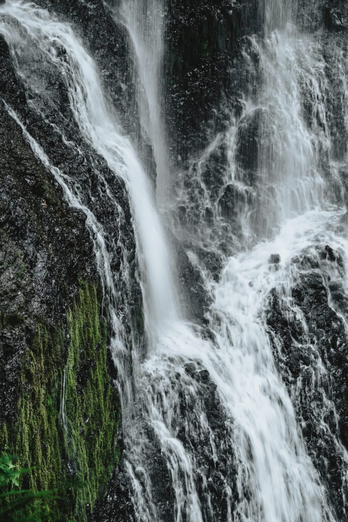 Dramatic waterfall cascading over rugged cliffs with mossy rocks and clear flowing water wallpaper