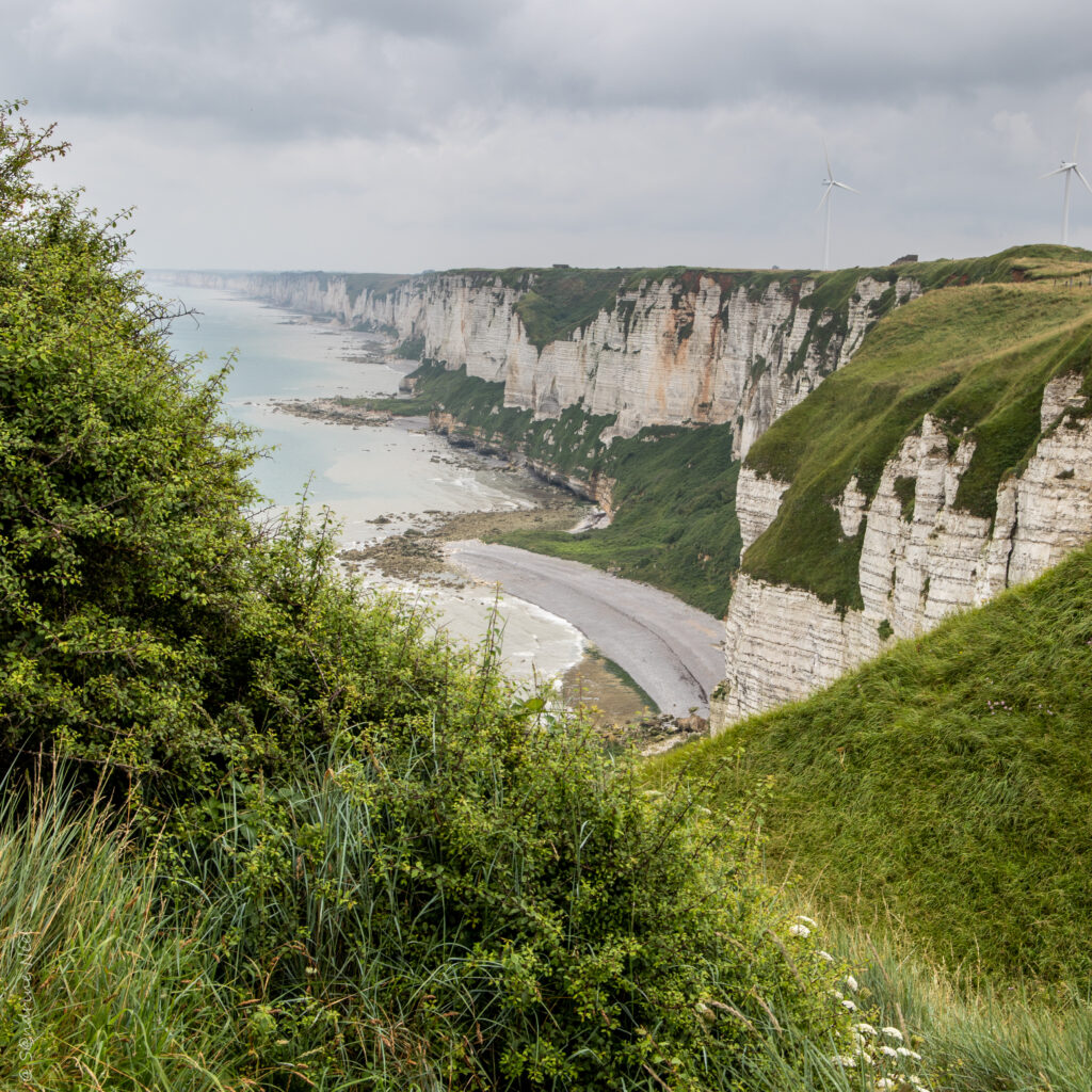 Dramatic white cliffs above rocky coastline with green grass and cloudy sky sea wallpaper background