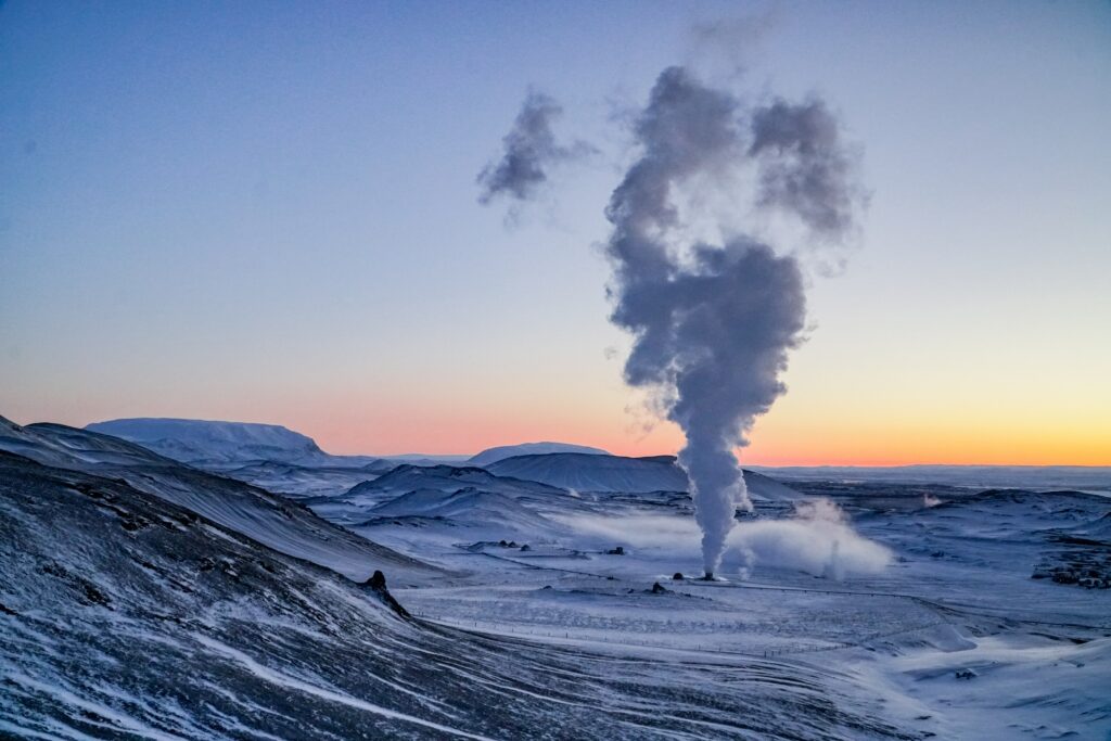 Winter geyser erupting steam at sunrise snowy hills mountains natural landscape wallpaper