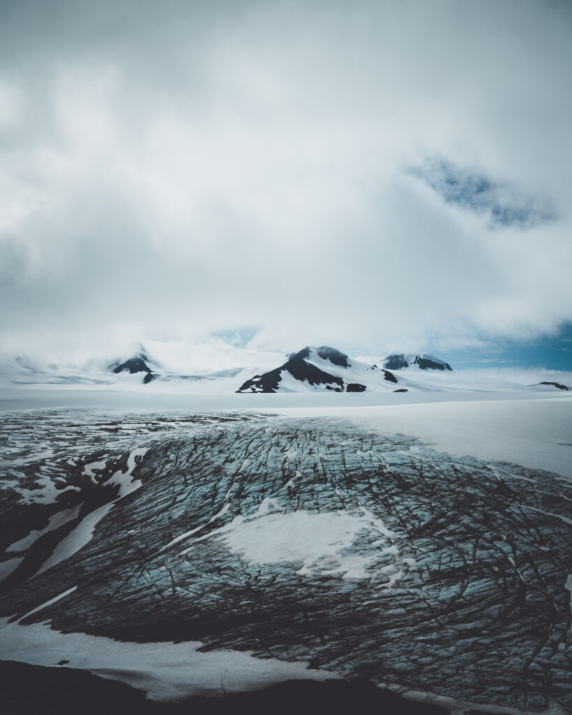 Snow-covered mountains and hills under moody clouds winter landscape wallpaper background