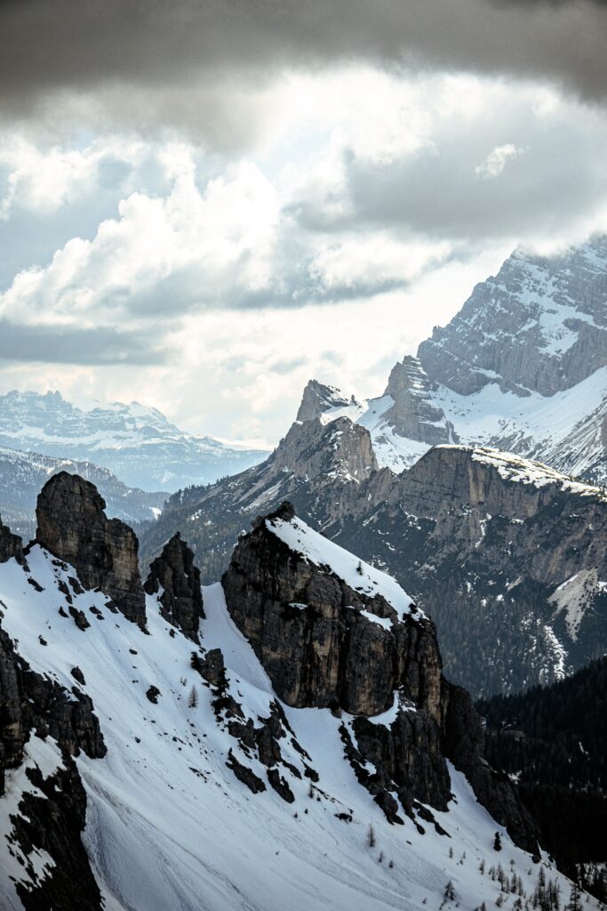 Dramatic winter mountain landscape with snowy slopes rocky outcrops and moody alpine sky wallpaper