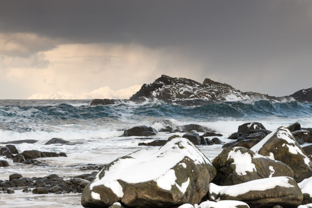Stormy winter seascape with crashing waves icy rocks and snowy coastal stones wallpaper background