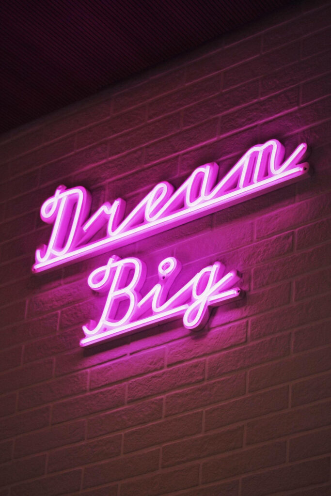 Dream Big Cursive Pink Neon Sign Wallpaper on Brick Background