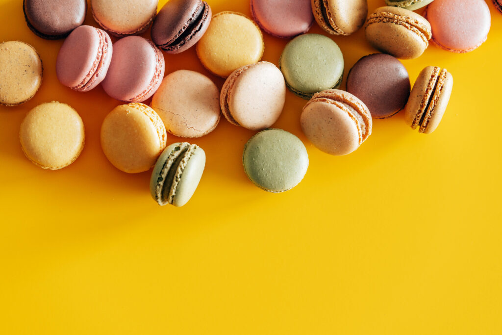 Pretty Pastel Macarons Posing Against a Sunny Yellow Canvas Wallpaper