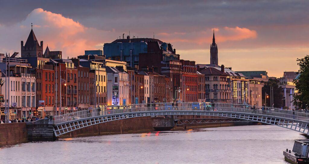 Dreamy evening view of Dublin Hapenny Bridge with historic riverside buildings at sunset Wallpaper