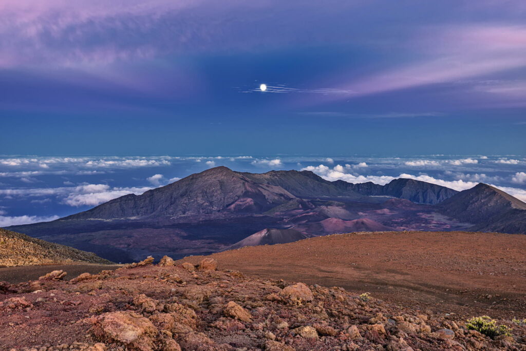 Breathtaking landscape wallpaper with rugged rocks rolling mountains vibrant dusk sky and glowing moon