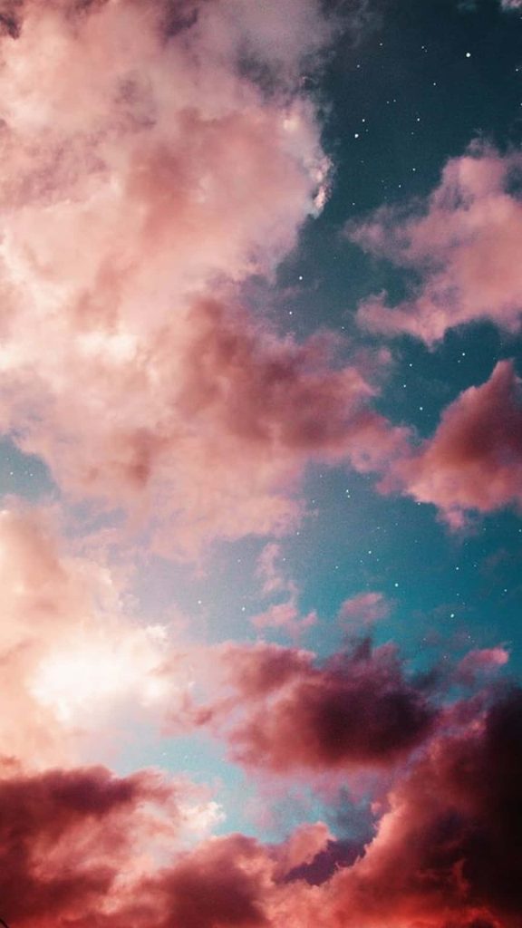 Soft pink clouds floating over a deep blue starry night sky serene phone wallpaper background