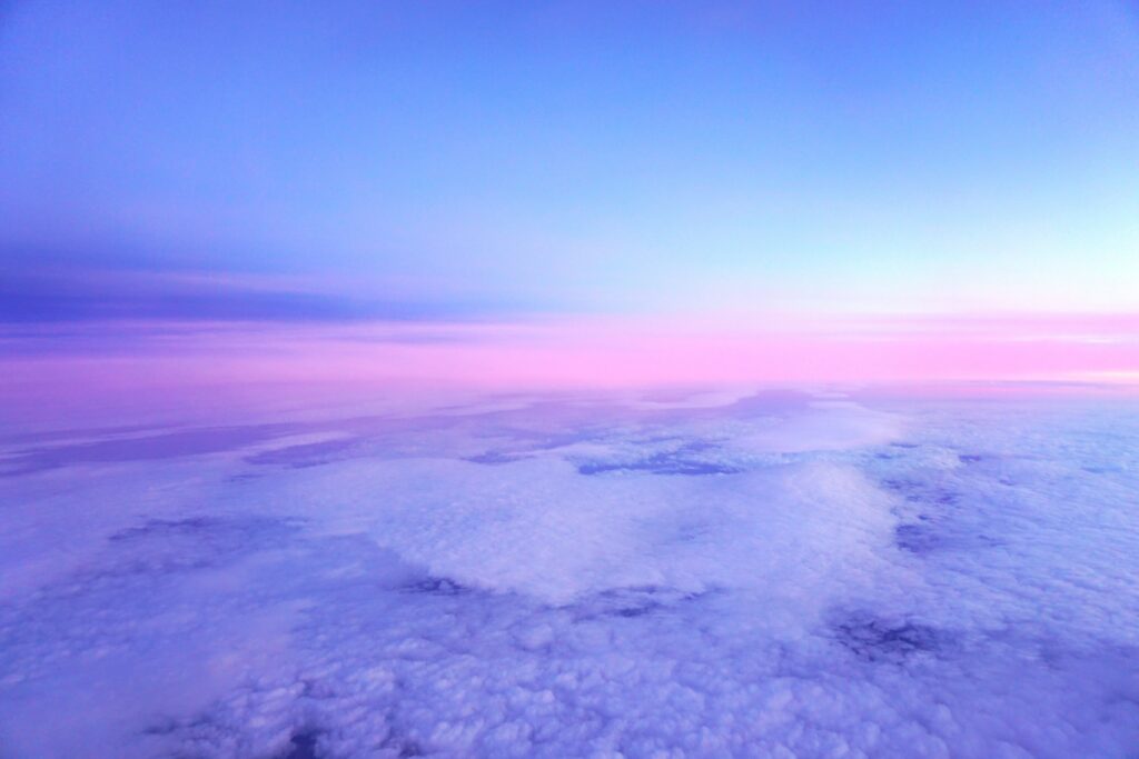 Dreamy porous clouds in pink and lilac hues over smooth gradient sky wallpaper background