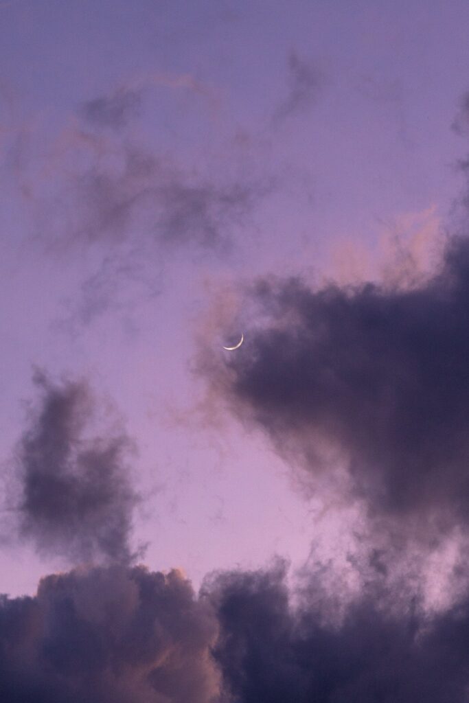 Serene purple sky with wispy clouds and delicate crescent moon calm dreamy night wallpaper background
