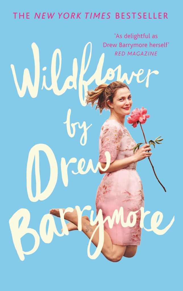 Drew Barrymore smiling holding pink flower bright blue background cheerful Wildflower wallpaper