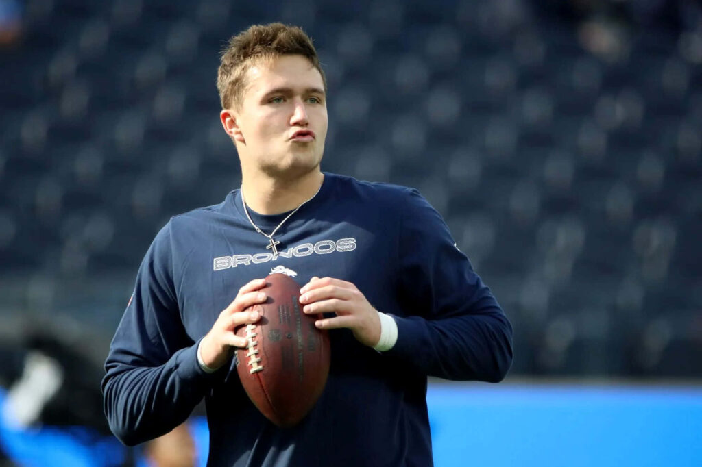 Drew Lock Denver Broncos quarterback focused during pregame warmup holding football in stadium Wallpaper