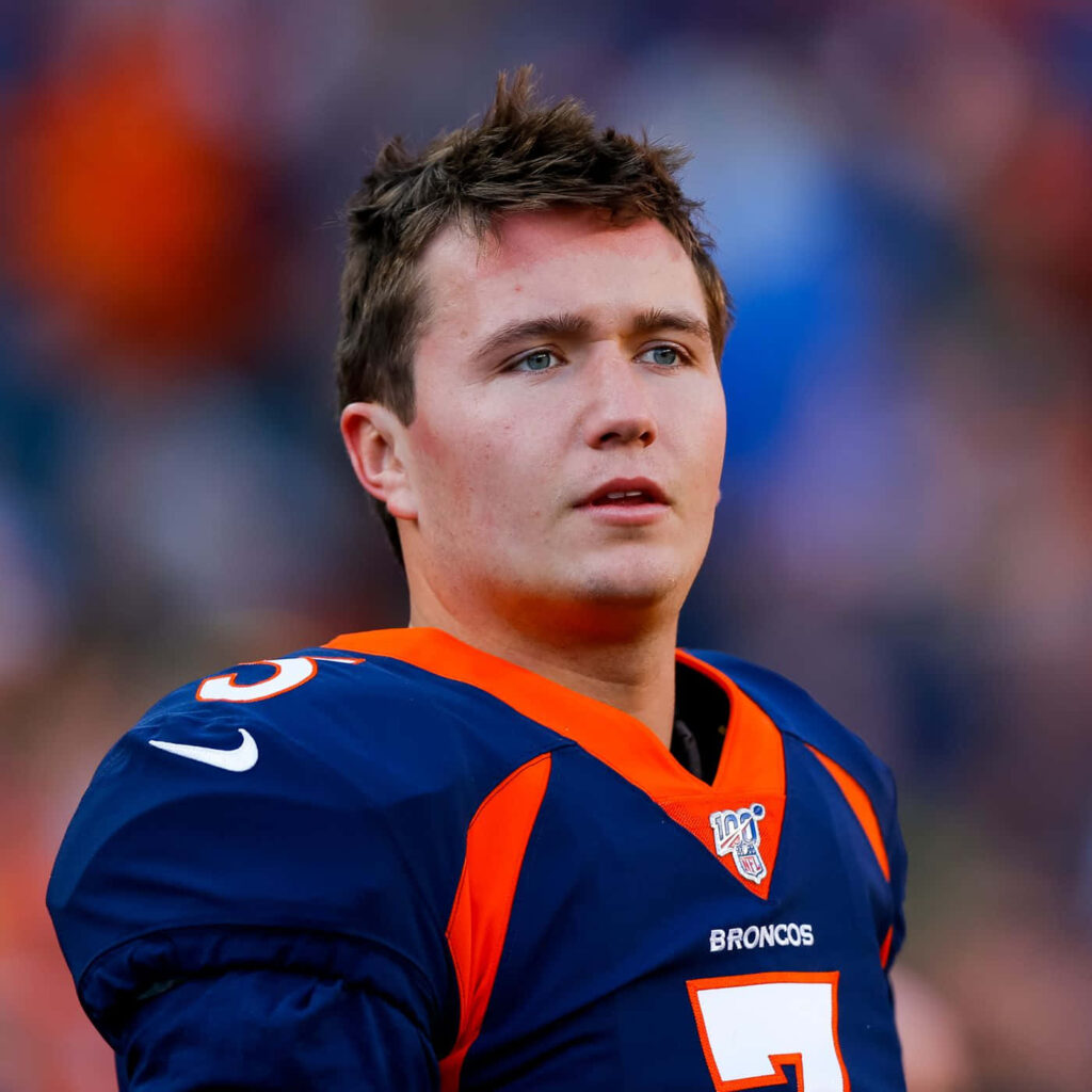 Drew Lock Denver Broncos quarterback in navy orange uniform focused game day stadium background Wallpaper