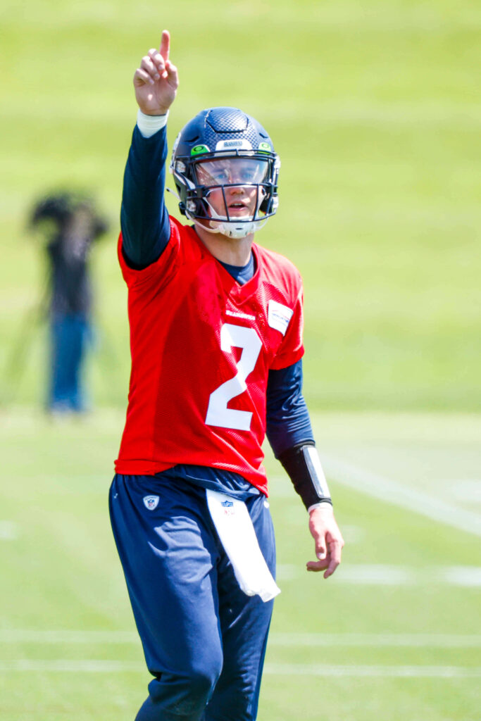 Quarterback Drew Lock in red jersey pointing during intense practice on green football field background Wallpaper
