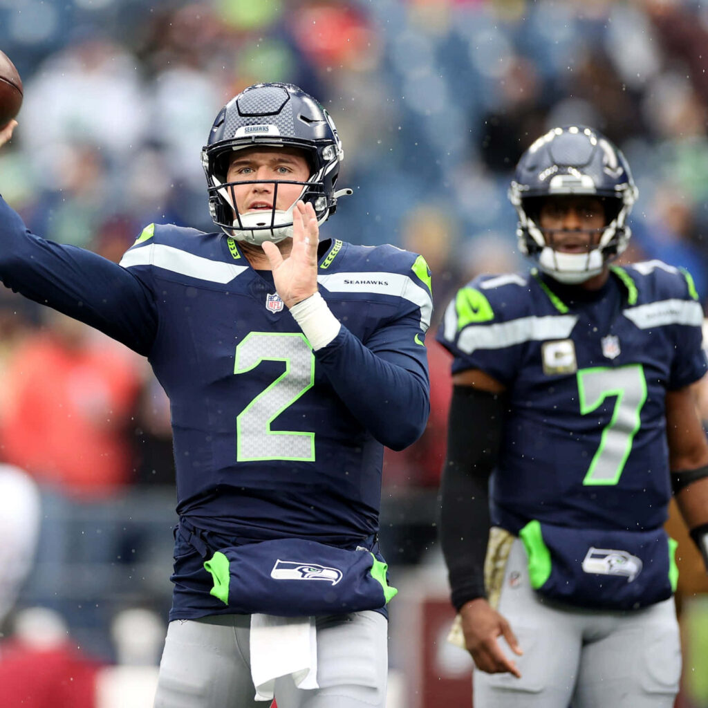 Seahawks quarterback Drew Lock warming up in navy and green uniform on field with teammate Wallpaper