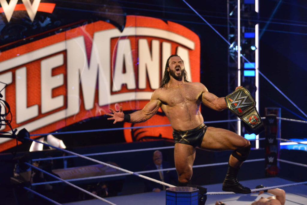 Drew McIntyre triumphs holding WWE Championship belt at WrestleMania with dramatic lighting Wallpaper