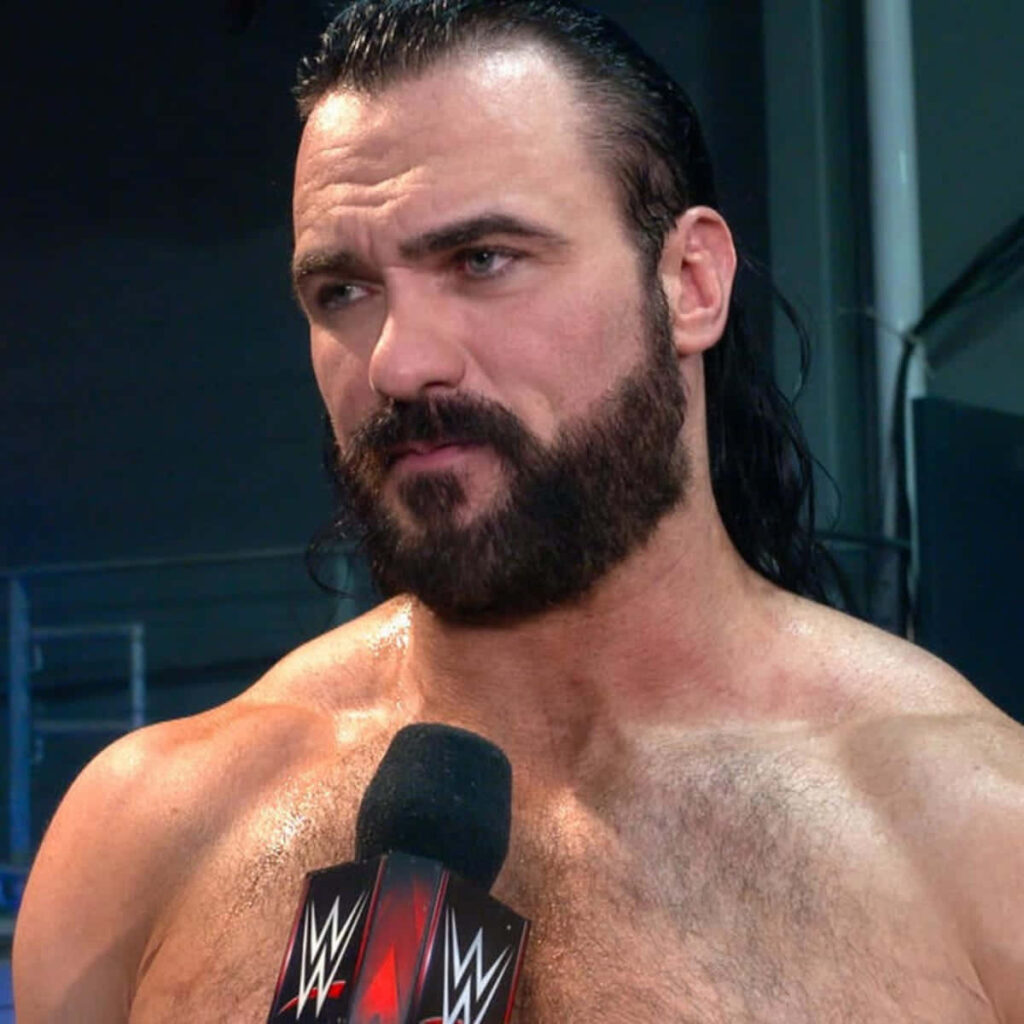 Close-up of WWE wrestler Drew McIntyre with intense expression wet hair beard and microphone background Wallpaper