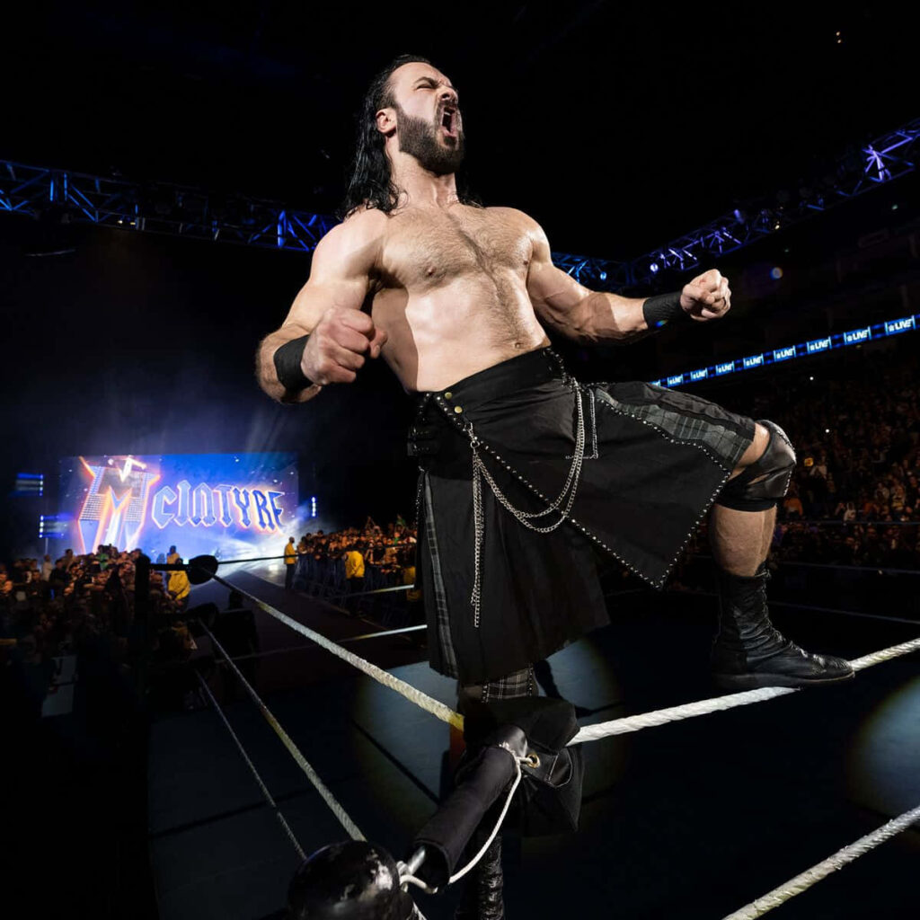 Drew McIntyre roaring in wrestling ring with dramatic lighting and packed arena background Wallpaper
