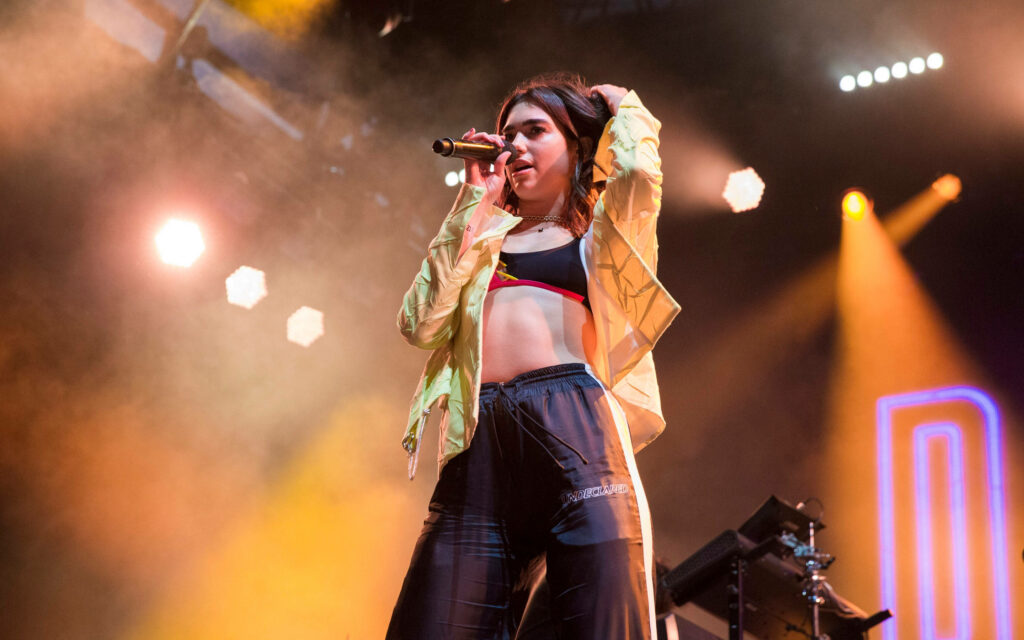 Dua Lipa Performing Live: Vibrant Energy & Style Under Dramatic Lights Wallpaper