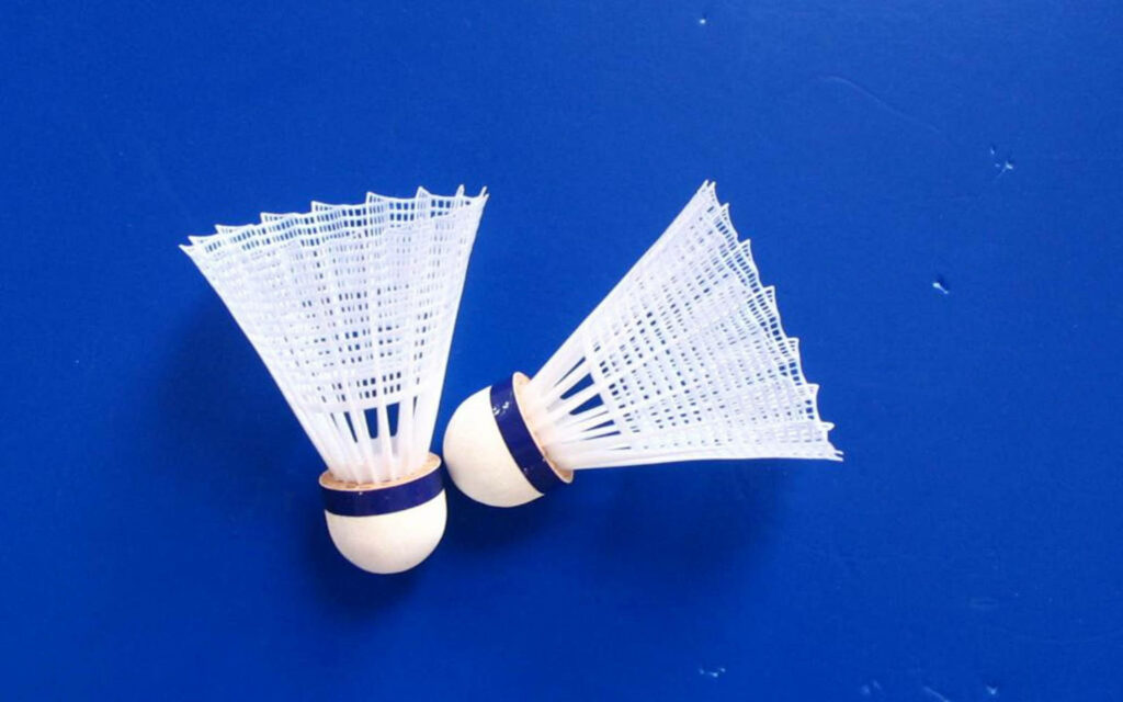 Colorful Badminton Shuttlecocks Resting on a Vibrant Blue Background Wallpaper