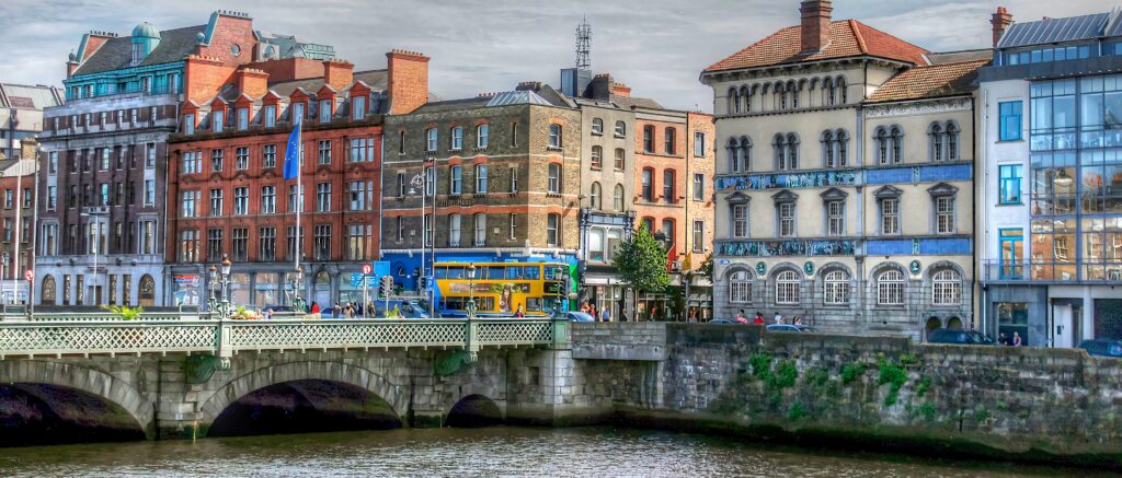 Panoramic Dublin cityscape with historic stone bridge classic brick buildings and yellow bus wallpaper