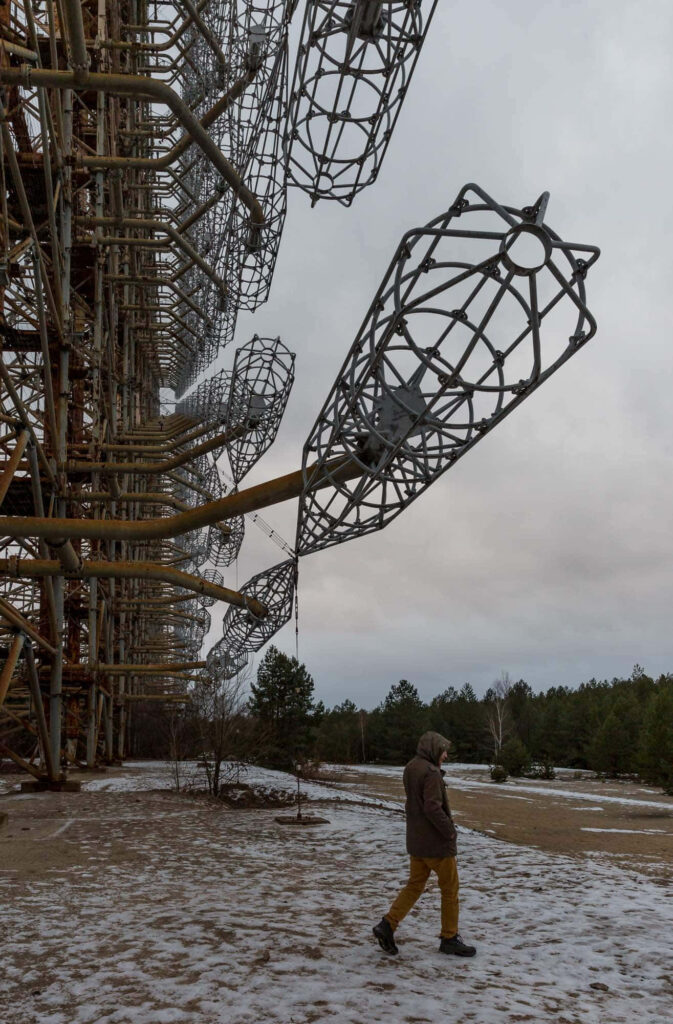 Man walking near giant Duga radar antenna in Chernobyl winter landscape cold war relic wallpaper