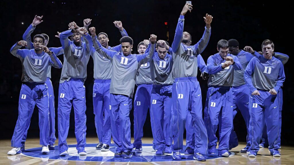 Duke Blue Devils basketball team celebrating on court in blue grey warm-up suits dynamic wallpaper