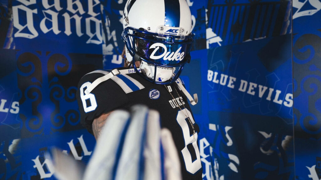 Duke Blue Devils football player in uniform with extended gloved hand on dynamic blue background Wallpaper