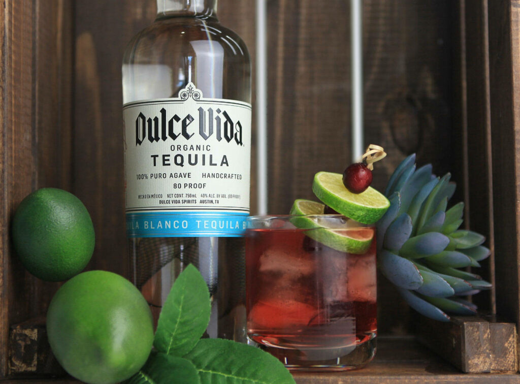 Dulce Vida Blanco Tequila bottle with lime cherry cocktail fresh limes succulent rustic wood background Wallpaper