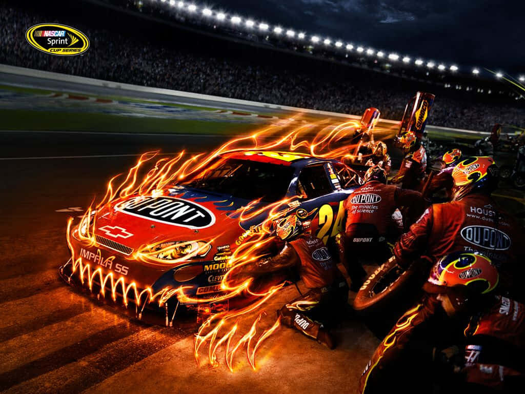 Dupont Chevy SS Nascar race car with flaming monster graphics and pit crew under stadium lights Wallpaper