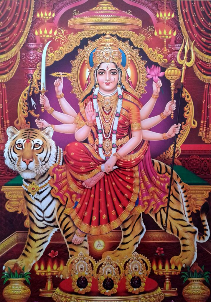 Durga Devi portrait on tiger with red saree gold jewelry multiple arms holding weapons lotus flowers Wallpaper