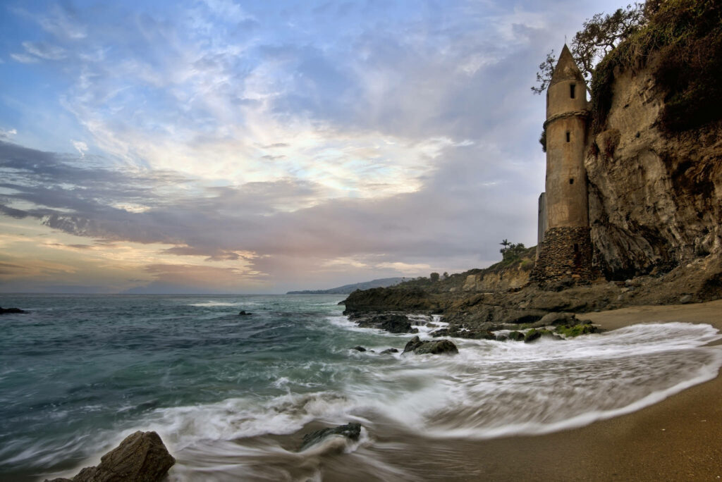 Dusk Serenade: Majestic Waves Caressing Rocky Shoreline in Stunning Beachscape Desktop Wallpaper