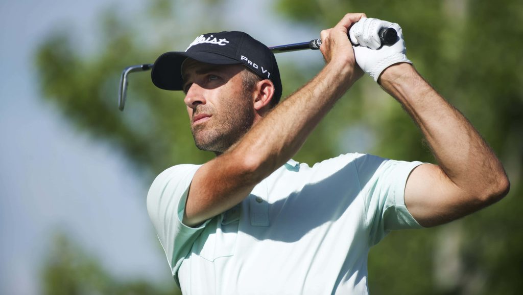 Dustin Johnson mid-swing in light blue polo and Titleist hat on blurred green golf course background Wallpaper