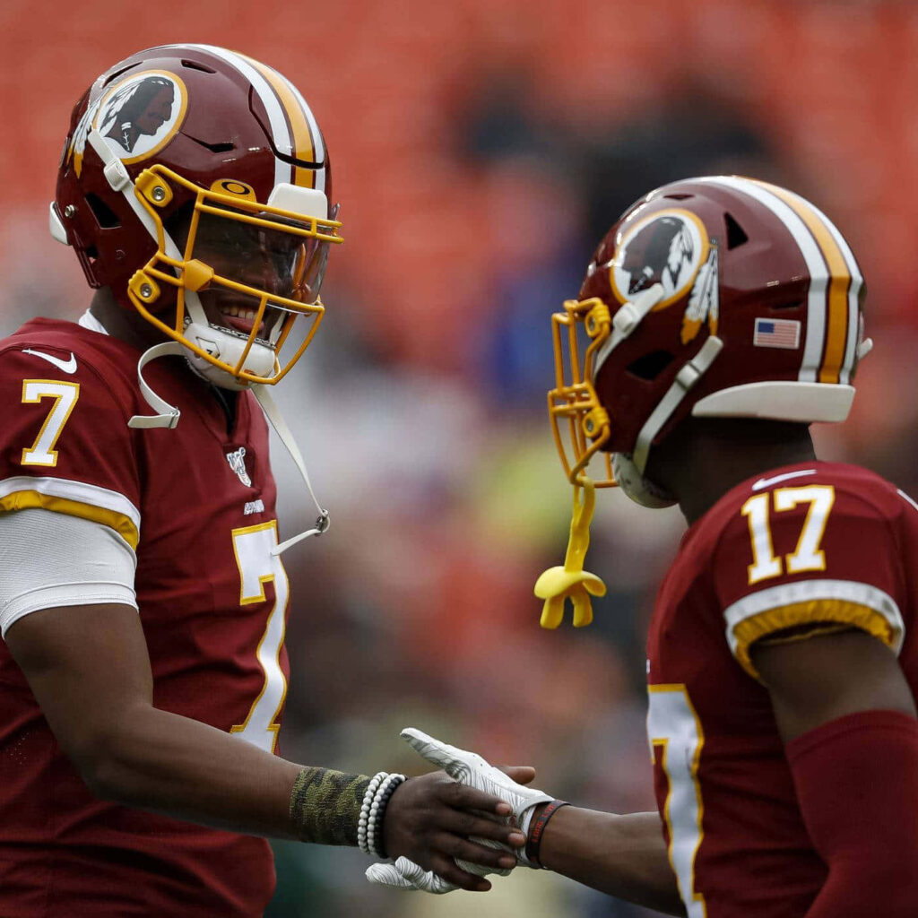 Dwayne Haskins shaking hands with teammate in burgundy gold Washington football uniforms on field Wallpaper