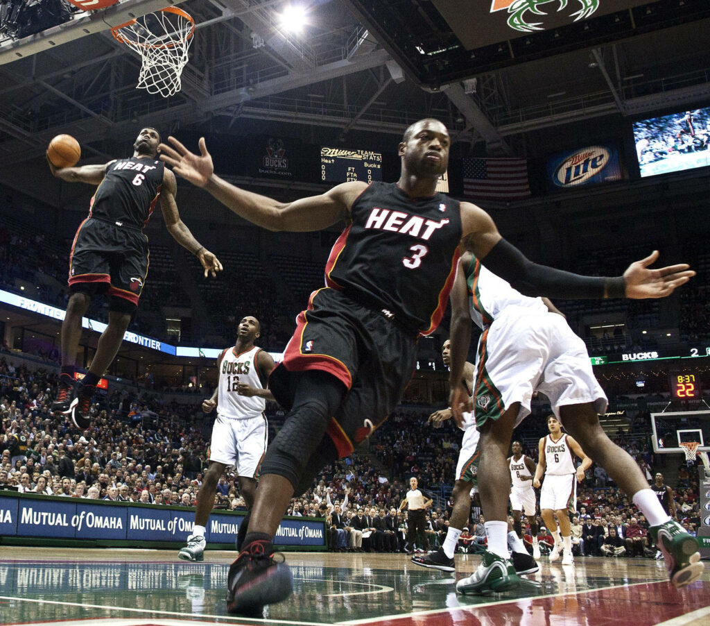 Dwyane Wade celebrating Miami Heat slam dunk contest with teammate soaring in packed arena Wallpaper