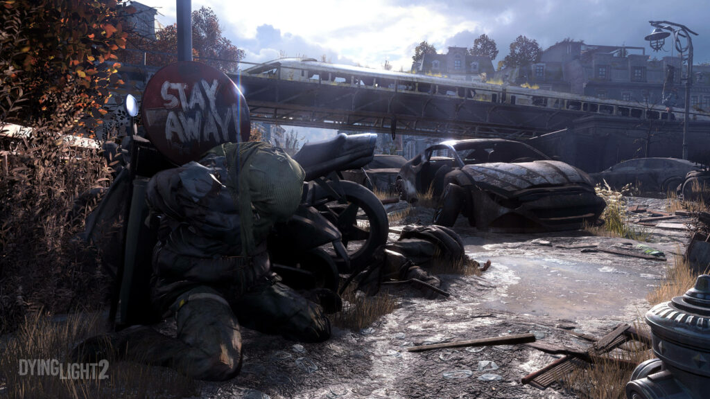 Dying Light 2 wallpaper with Stay Away sign on decayed figure amid abandoned cars and urban decay