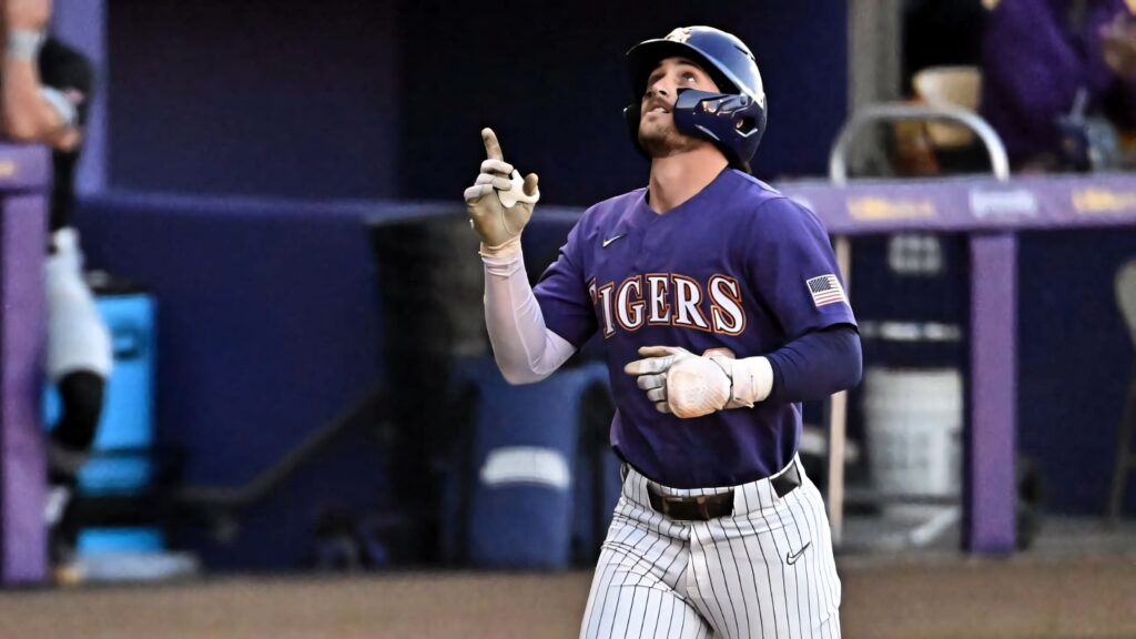 Dylan Crews celebrates a powerful hit wearing purple Tigers jersey on vibrant baseball field background Wallpaper