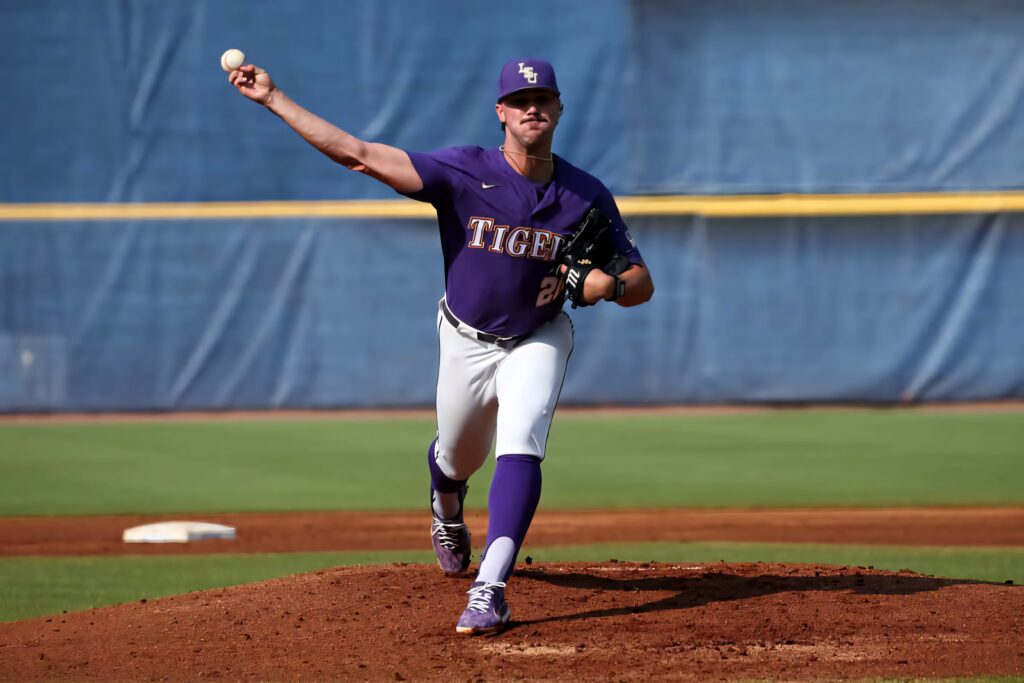 Dylan Crews pitching for LSU in purple and gold uniform on sunny day at baseball field Wallpaper
