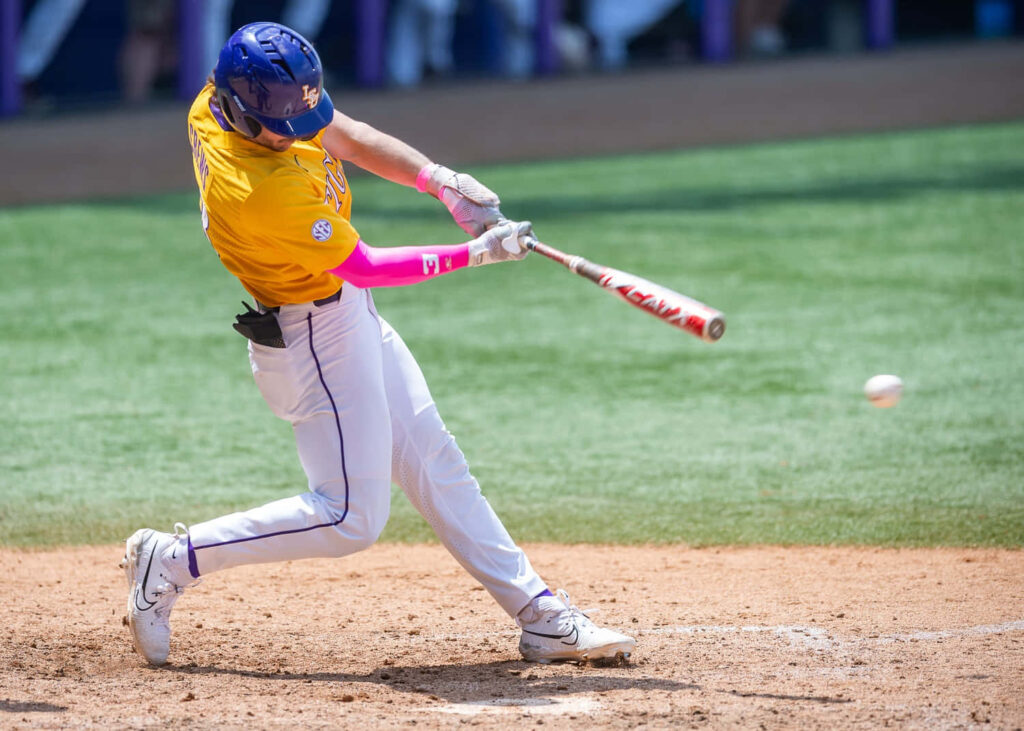 Dylan Crews mid-swing in yellow jersey blue helmet vibrant baseball action on sunlit field wallpaper