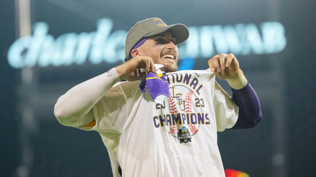 Dylan Crews smiling in National Champions shirt with glowing stadium celebrating baseball win Wallpaper