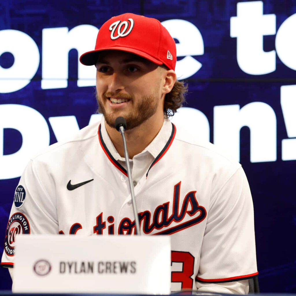 Baseball player Dylan Crews at press conference in Washington Nationals cap and jersey vibrant wallpaper