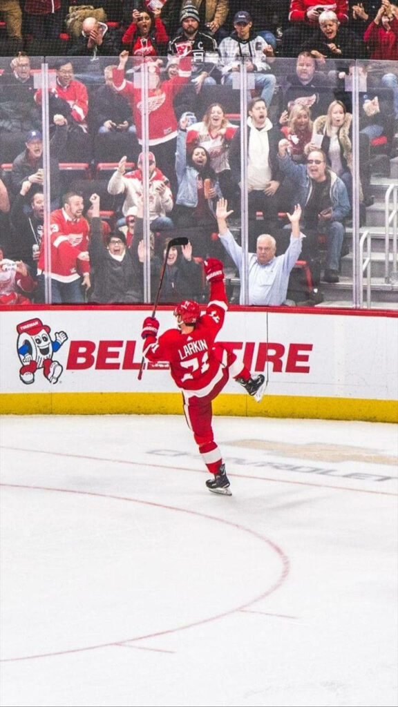 Dylan Larkin Detroit Red Wings celebrates on ice with fans cheering vibrant hockey game energy Wallpaper