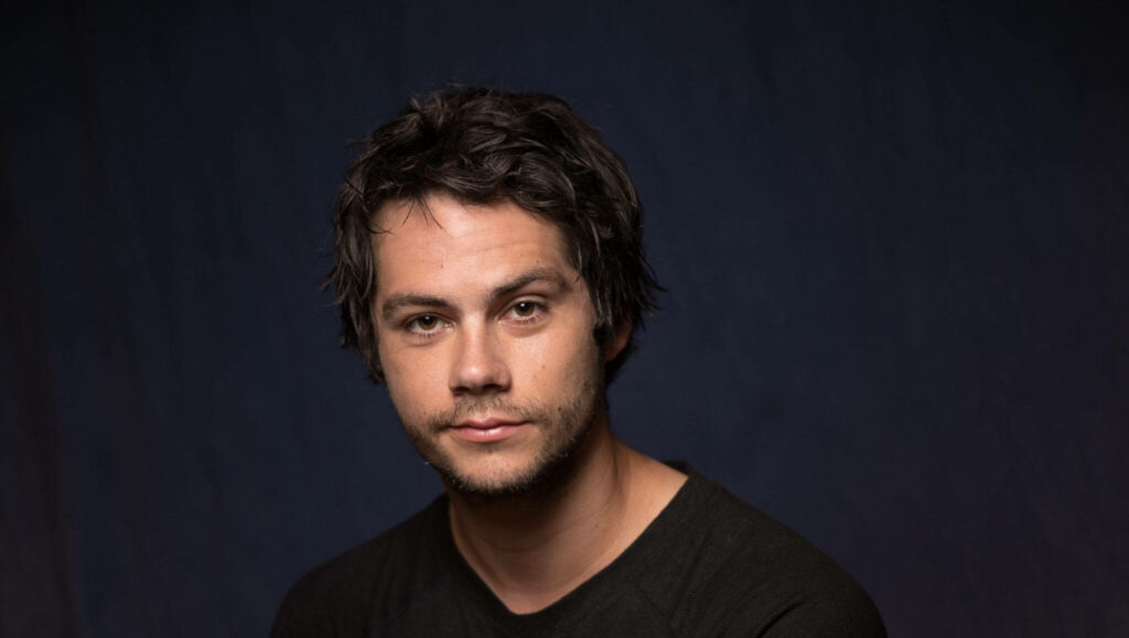 Close-up of Dylan O'Brien with messy hair and soft lighting on dark minimalist background wallpaper