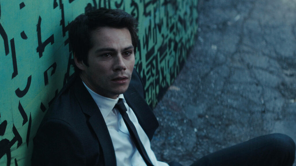 Dylan O'Brien in dark suit against graffiti wall tense urban scene Flashback psychological thriller Wallpaper