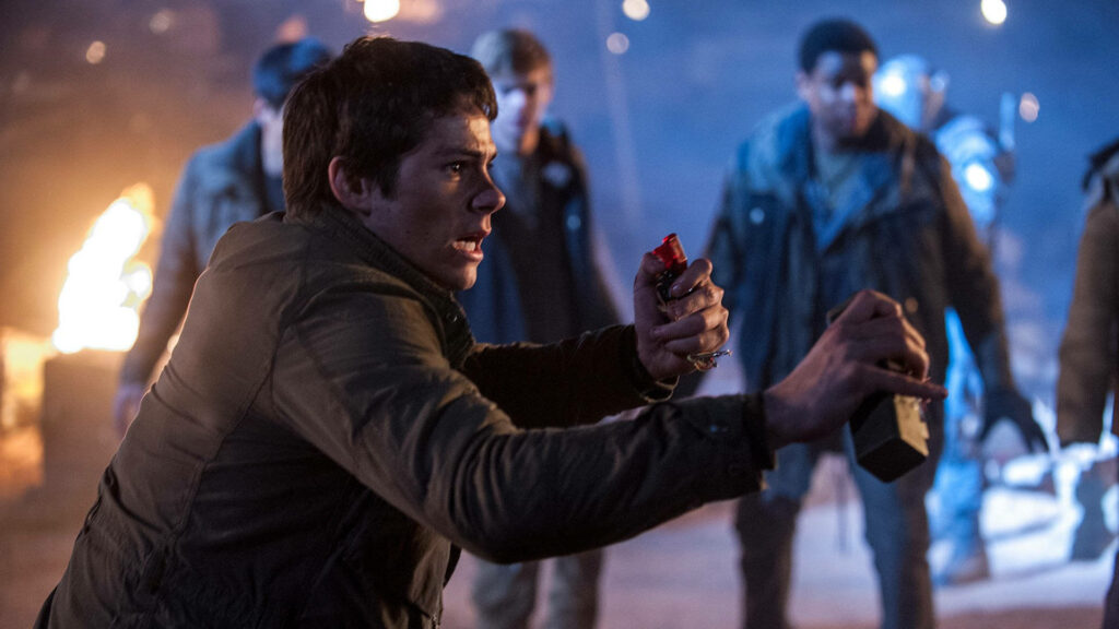 Dylan O'Brien intense action scene gripping detonator flames blurred figures HD wallpaper background