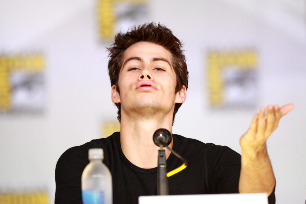 Dylan O'Brien blowing a playful flying kiss with warm natural light and soft focus background Wallpaper